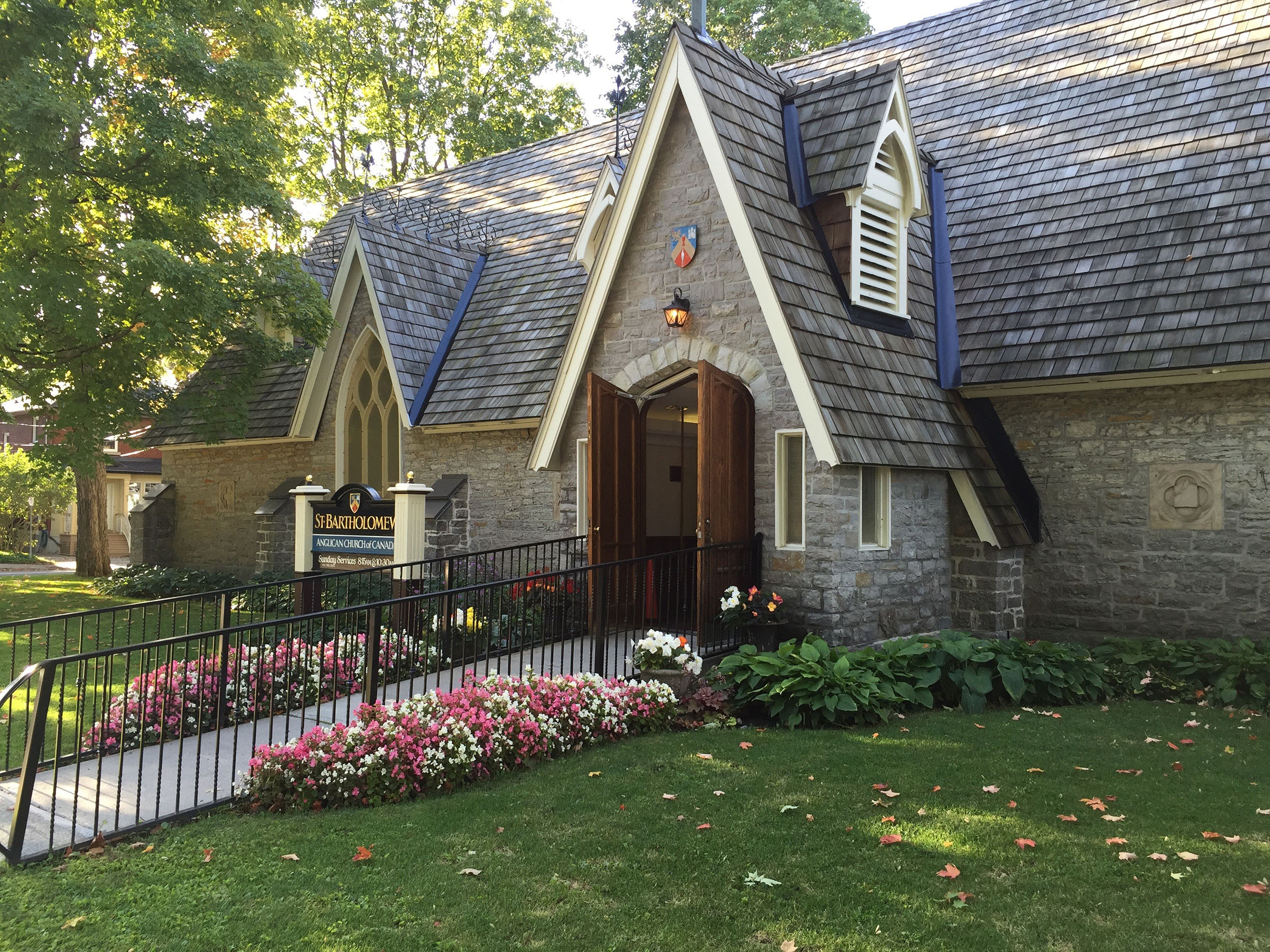 Exterior view of the stone church and its walkway lined with flowers.